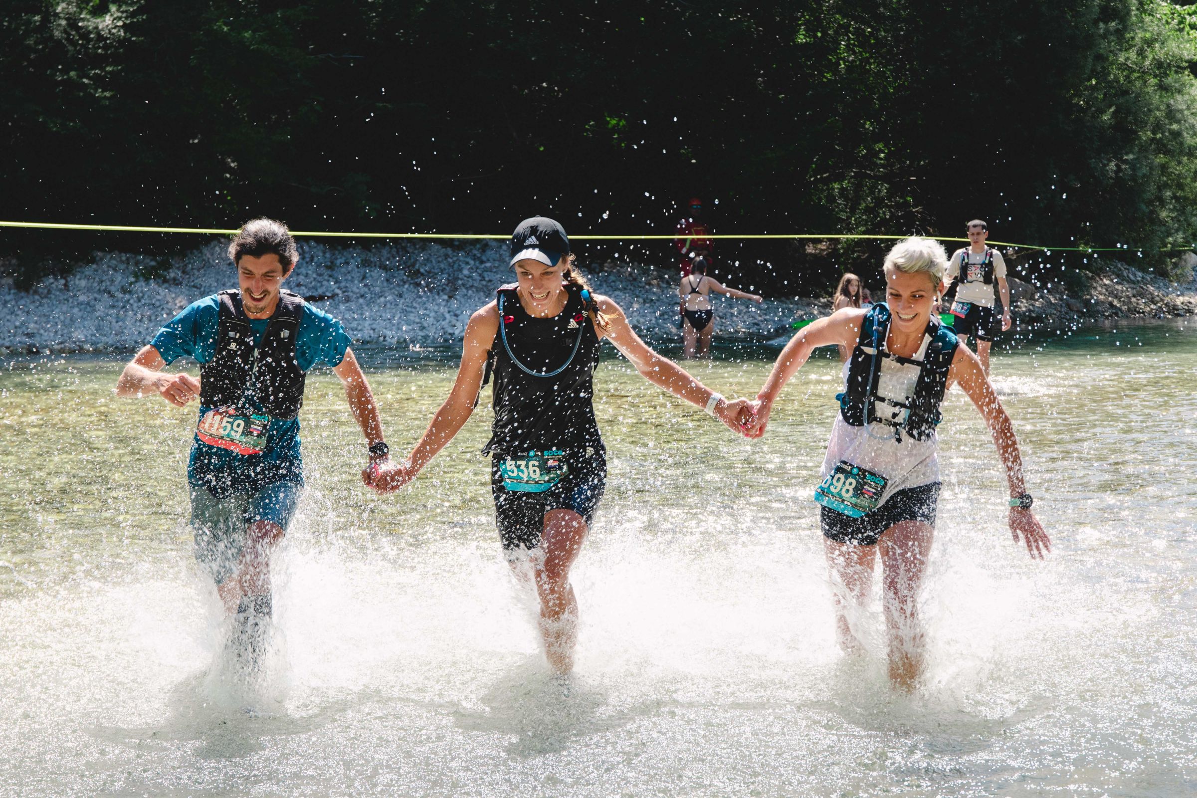 Tri tekačice prečkajo reko Tolminko na Soča Outdoor trail teku za začetnike
