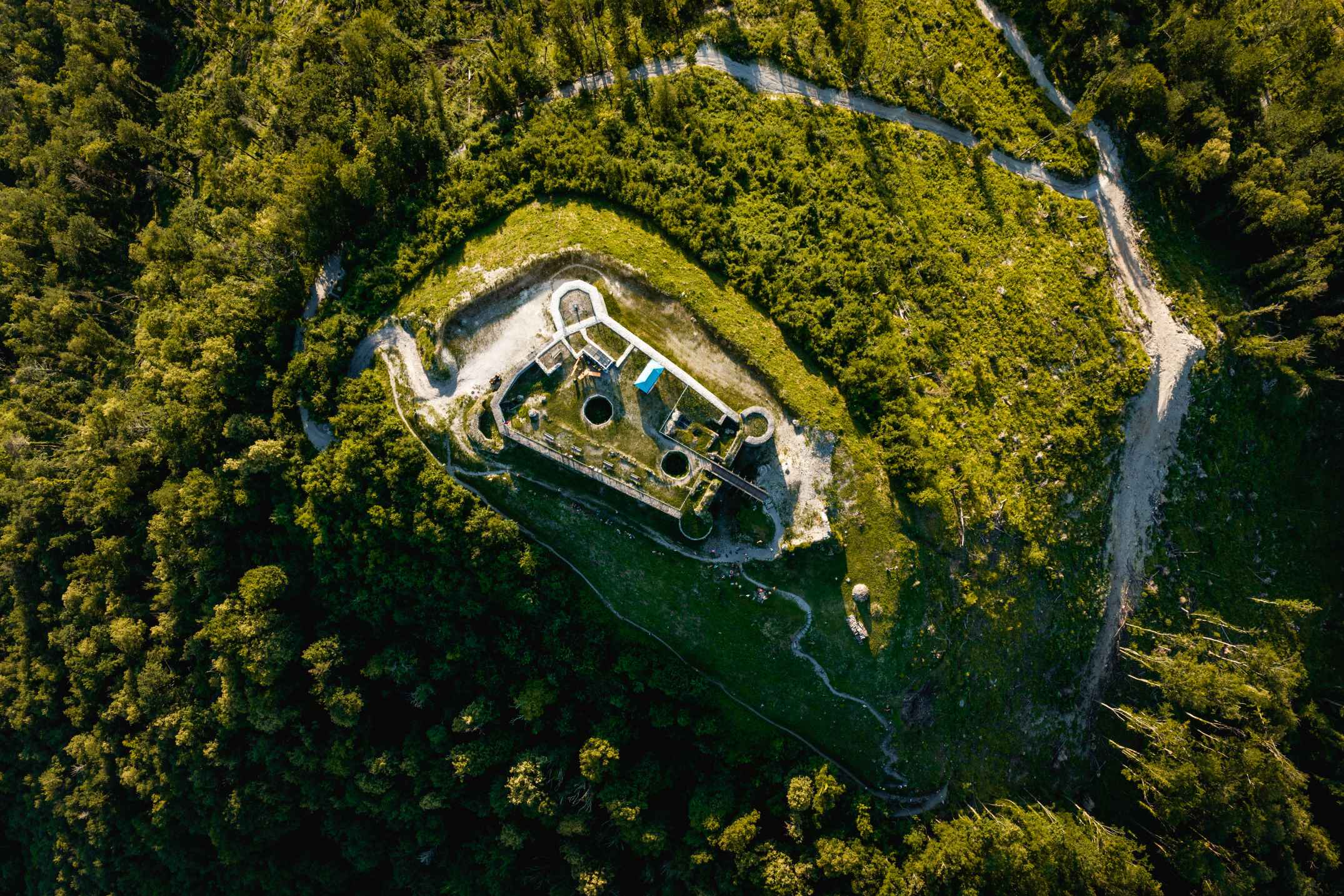 Zračni posnetek Tolminskega gradu, obdanega z gozdom, med vertikalnim tekom na Soča Outdoor Festivalu